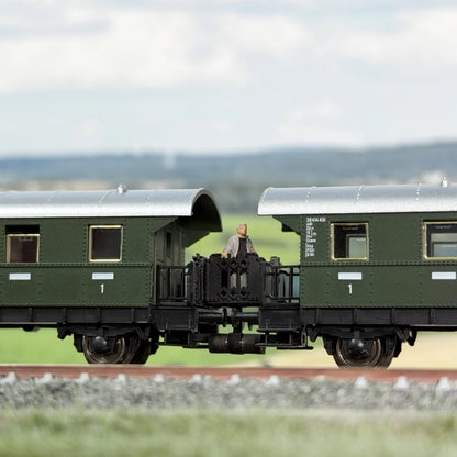 Klassische Übergangsbrücke zwischen zwei Fleischmann Donnerbüchsen (Länderbahnwagen). Auf dem Übergang steht ein reisender Mann.