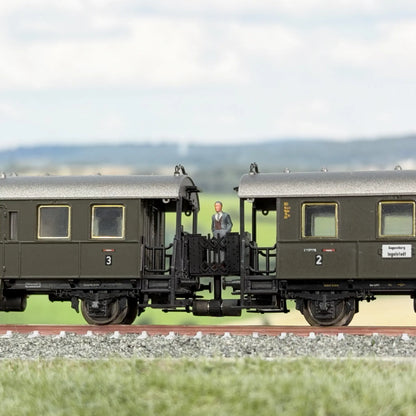 Minitrix Länderbahnwagen (Donnerbüchse), dazwischen eine Verbindungsbrücke im Minitrix Design. Auf der Brücke steht ein Fahrgast, ein Mann mit grauem Anzug und schaut sich die Landschaft an